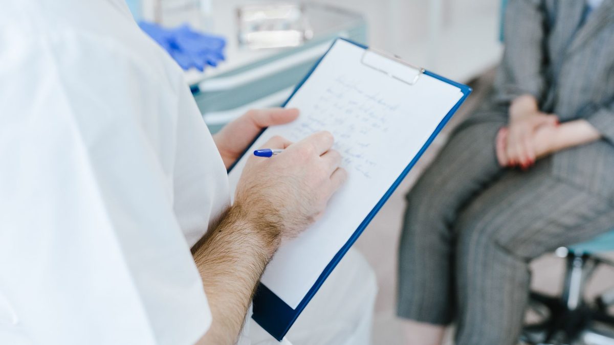 Un professionnel de santé prend des notes sur un dossier pendant une consultation